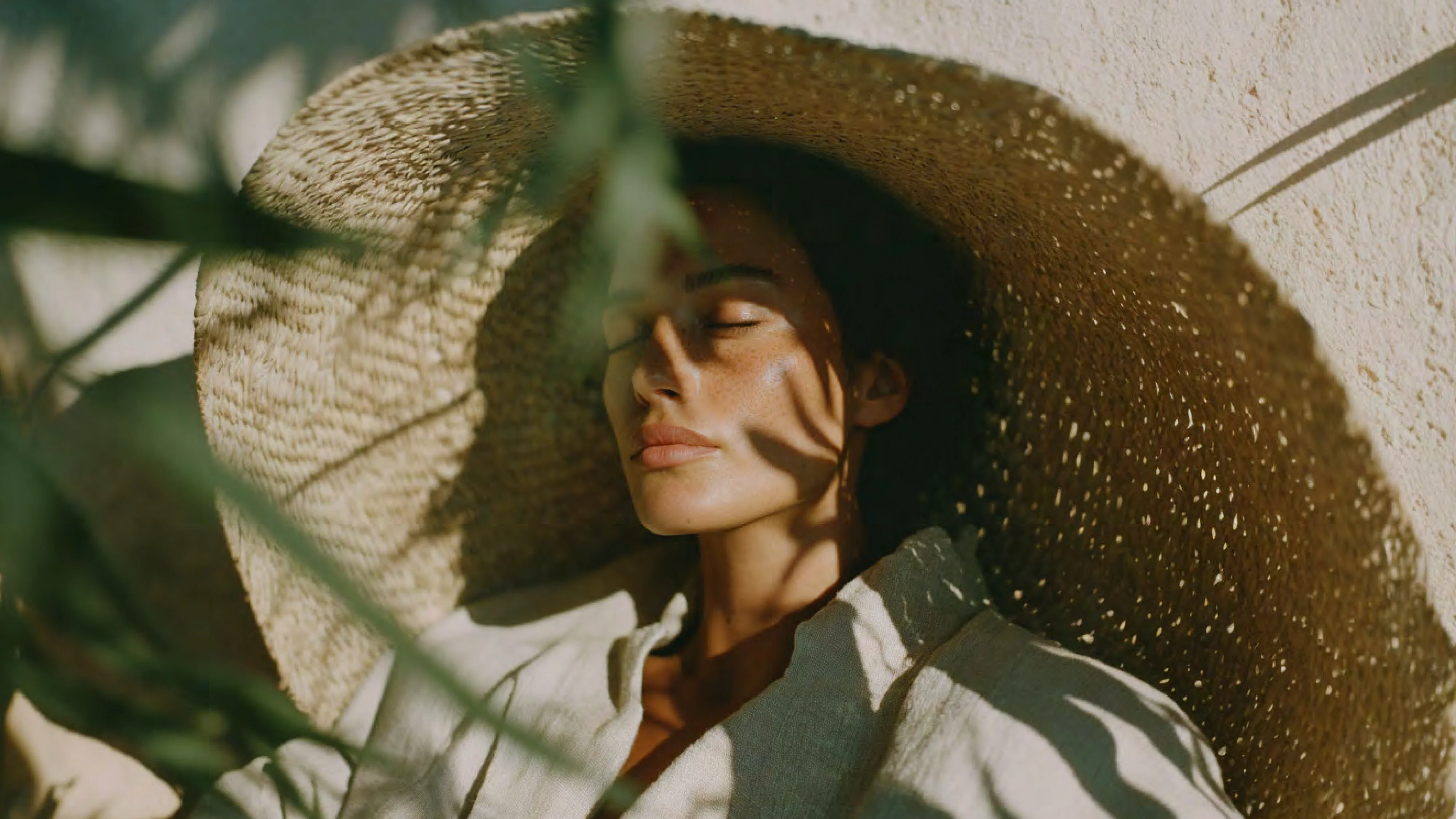 Face in leaf dappled shadow, straw hat